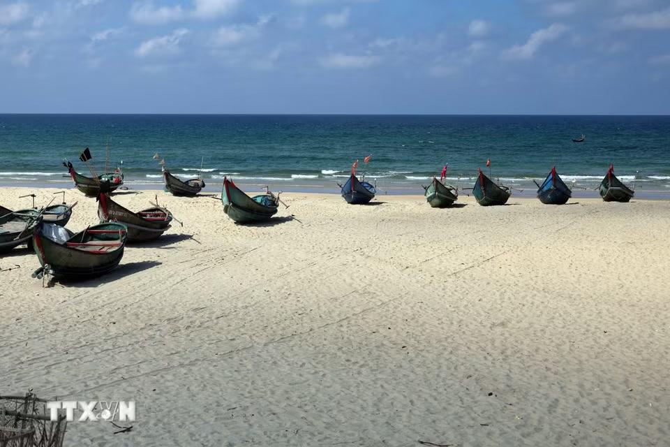Những chiếc thuyền khai thác hải sản nhỏ của ngư dân nằm "phơi mình" trên bãi cát trắng mịn tạo thành một bức tranh tuyệt đẹp. (Ảnh: Đỗ Trưởng/TTXVN)