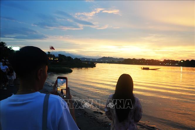 Giới trẻ chụp ảnh lưu lại cảnh đẹp của hoàng hôn từ bờ Nam sông Hương, thành phố Huế.
