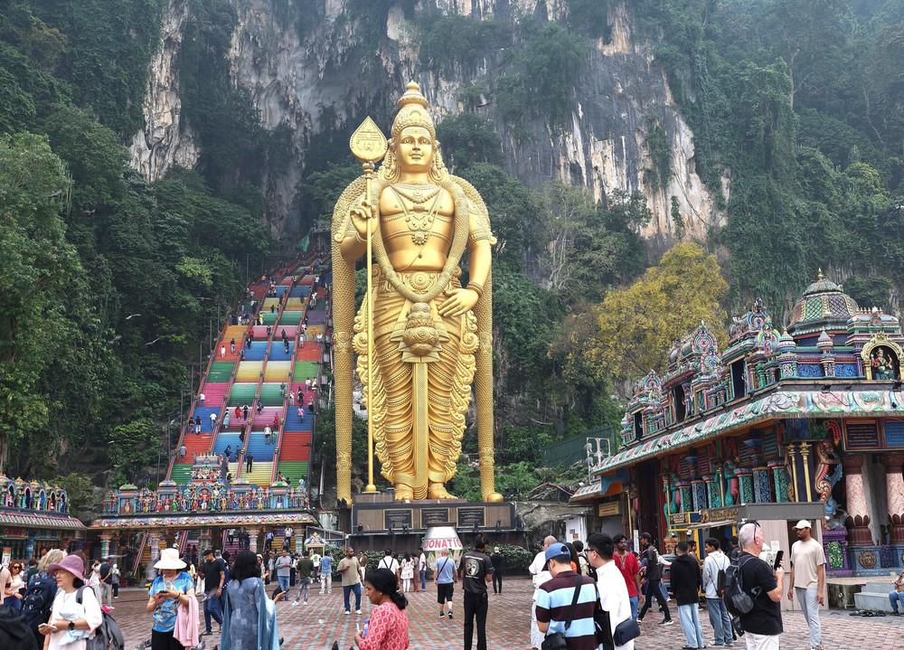Tượng thần Murugan trước lối lên Động Batu và phía sau là cầu thang nhiều màu dẫn du khách lên khu đền và hang động bên trong núi đá vôi. Ảnh: Thanh Bình – PV TTXVN tại Kuala Lumpur