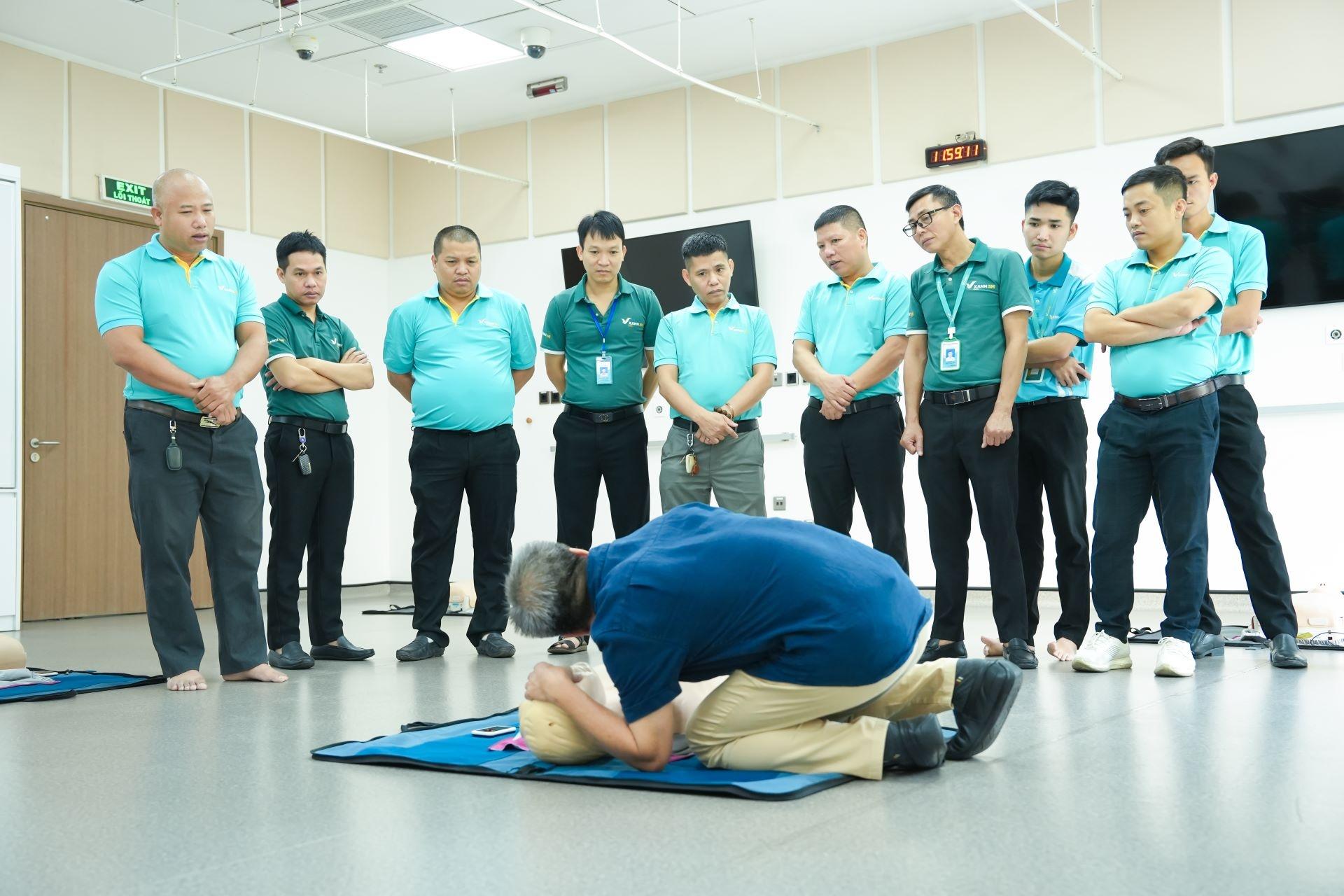  Đội ngũ tài xế quan sát chuyên gia y tế làm mẫu thao tác kiểm tra hô hấp của nạn nhân trên mô hình. 