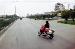 Nữ 'ninja' chở con nhỏ vừa lái xe vừa buông tay cởi áo mưa trên quốc lộ khiến người xem thót tim
