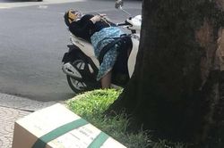 Quá mệt vì 'vật lộn' với nắng nóng gay gắt, người phụ nữ trùm kín như ninja ngả lưng trên xe SH ngủ bên lề đường