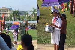 Bức ảnh người bà lom khom che ô cho cháu tập nghi thức đội giữa trưa nắng
