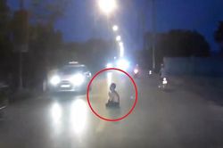 Người đàn ông cởi trần, chắp tay ngồi giữa đường