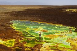 Du khách dũng cảm đi qua hồ bậc thang đang sủi bọt trên sa mạc Ethiopia
