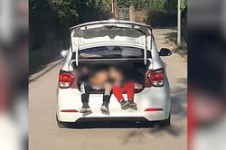 2 bé trai vô tư đùa nghịch khi ngồi vắt vẻo trong cốp sau ô tô đang chạy