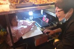 Cô bé 7 tuổi học bài dưới gầm sạp hàng của mẹ