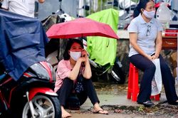 Phụ huynh ngồi đợi con dưới mưa ở TP.HCM
