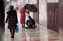 Xúc động cảnh cô gái cầm ô che cho người bị tật 2 chân dưới mưa