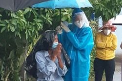 Nữ tình nguyện viên ở TP.HCM cầm ô che cho cụ già dưới trời mưa lớn