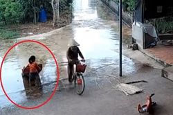 Bé gái đội mưa hì hục giúp mẹ 'chạy' đồ đang phơi