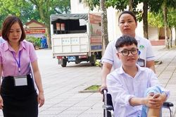 Nhân viên y tế đẩy xe lăn đưa nam sinh đến phòng thi tốt nghiệp