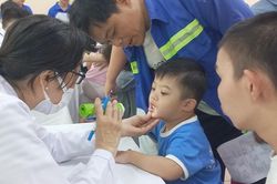 Ba người cùng cân một em nhỏ trong ngày khám sức khỏe đặc biệt
