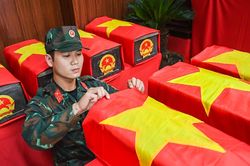 Chiến sĩ trẻ tự nguyện nhận nghi thức phủ Quốc kỳ lên hài cốt liệt sĩ