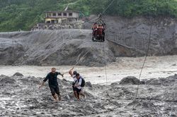 Những người bị mắc kẹt ở vùng lũ Nepal vượt sông Trishuli bằng dây cáp trượt