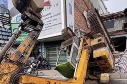 Xe múc đang tháo dỡ nhà bất ngờ lật ra đường