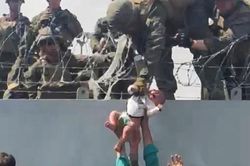 Trẻ em được chuyền qua rào kẽm gai ở sân bay Kabul