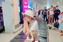 Cô gái ngồi xổm trên băng chuyền hành lý ở sân bay