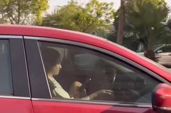 Người phụ nữ gác chân lái ô tô, tay vẫn mải bấm điện thoại trên phố Hà Nội