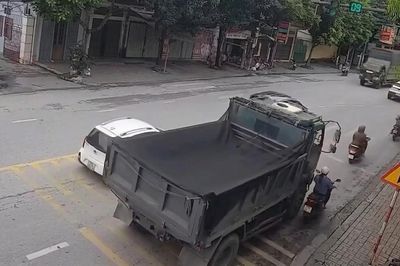 Xe ben vượt phải ở giây cuối đèn xanh, ép xe máy vào lề rồi cán qua