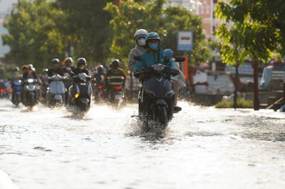 Triều cường dâng cao giữa trời nắng nóng, người dân TP.HCM bì bõm lội nước đi về