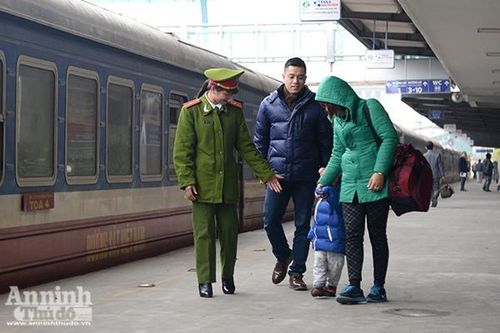 Nữ chiến sỹ Trạm Cảnh sát Ga Hà Nội trò truyện với một em bé theo gia đình về quê ăn Tết