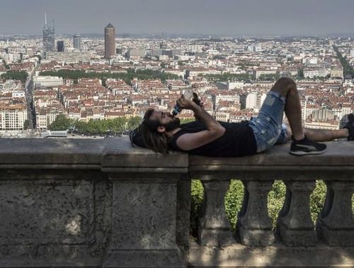  Người đàn ông tranh thủ uống nước, nghỉ ngơi dưới bóng râm ở Lyon, Pháp 