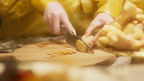 Mặc dù ăn vận sang chảnh là vậy, nhưng cô nàng lại một mình đứng trong bếp để cắt gừng.