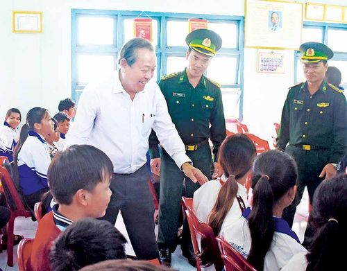 Phó Thủ tướng Thường trực Chính phủ Trương Hòa Bình (áo trắng) thăm hỏi, động viên các em học sinh tại buổi tặng xe đạp. Ảnh: M.T