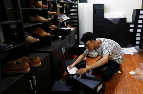 Ramdhany bên những chiếc giày từ da chân gà. Ảnh: Reuters