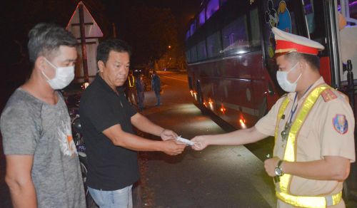 Thượng úy Đặng Phước Vĩnh phát khẩu trang y tế cho một hành khách tại cửa ô Hòa Phước.