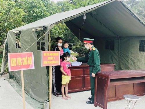 Đại úy Nguyễn Văn Hóa đo thân nhiệt cho mẹ con chị Nguyễn Thị H.