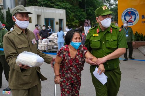  Chị Vũ Thị Xuyến (phố Đại La, Hà Nội) bị tai nạn, được cán bộ phường hỗ trợ đi lấy gạo. Chị cho biết rất vui khi nhận được số gạo tình thương này. 