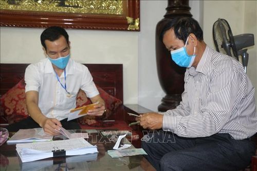 Cán bộ Bưu điện tỉnh Nghệ An chi trả lương hưu và trợ cấp bảo hiểm xã hội tại nhà cho người cao tuổi tại xã Nghi Phú, thành phố Vinh. Ảnh: Bích Huệ/TTXVN