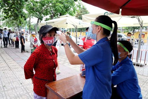  Người dân đo thân nhiệt trước khi vào nhận gạo. 