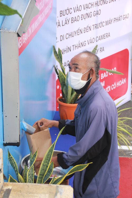Đến lượt, người dân tiến tới máy "ATM gạo" và nhìn vào camera nhận diện và gạo tự động "chảy" vào túi hứng