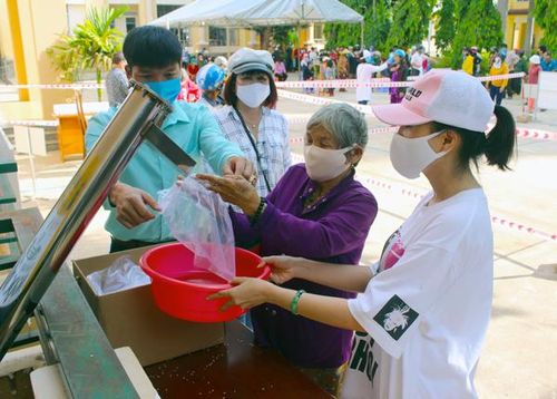 Chị Lê Hà (bìa phải) hỗ trợ người dân nhận gạo. Ảnh: P.L