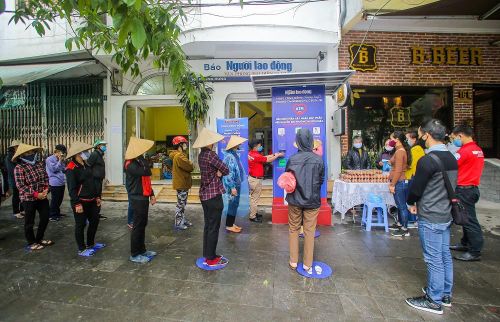 Người dân đến nhận gạo, thực phẩm bắt buộc phải giữ khoảng cách cộng đồng và đeo khẩu trang theo quy định. Ảnh: NGÔ NHUNG