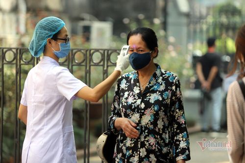 Người dân trước khi vào nhận gạo được nhắc nhở đeo khẩu trang, đo nhiệt độ và khử khuẩn tay để đảm bảo an toàn trong việc phòng, chống Covid-19