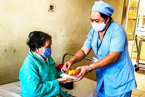 Cán bộ y tế Khoa Ngoại Cột sống mang cơm đến giường cho bệnh nhân.