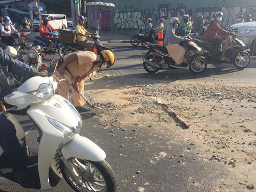 Chiến sĩ CSGT dọn đất đá rơi vãi trên mặt đường để người dân tiện lưu thông. 