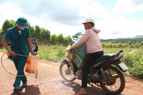 Người dân làng Bông Hiot mua nhu yếu phẩm sử dụng được lực lượng chức năng kiểm soát, phun thuốc kĩ lưỡng. 