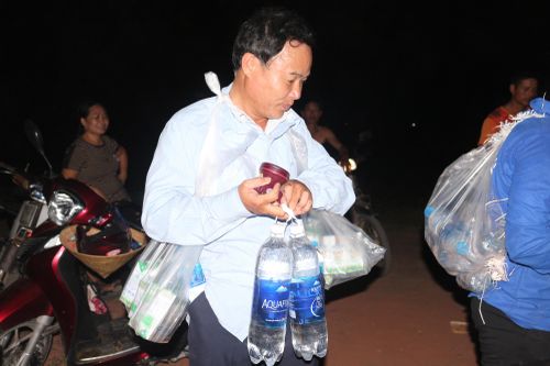 Nước uống, sữa, được người đàn ông đeo mang, xách tay chuẩn bị lên hiện trường đám cháy.