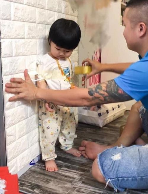 Thì vì trông con, người đàn ông này dùng băng dính dán con vào tường.