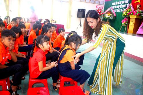 Cô giáo chỉnh sửa trang phục cho học sinh