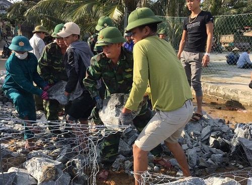 Cán bộ, chiến sĩ Đồn Biên phòng Lý Hòa và Đồn Biên phòng Roòn cùng với nhân dân địa phương gia cố kè chắn sóng biển bị sạt lở sau 2 trận lũ. Ảnh: Hoài Nam