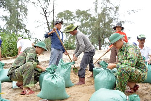 Cán bộ, chiến sĩ biên phòng cùng nhân dân buộc những bao đất, cát để gia cố bờ kè.