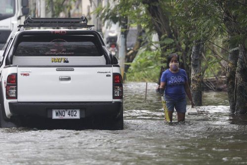  Người phụ nữ đi trên con đường bị ngập do bão Molave ở tỉnh Pampanga, miền bắc Philippines, hôm 26/10. 