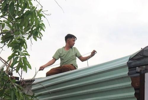 Người dân đang dùng dây thừng cột chắt mái tôn trên nhà.