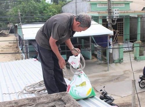 Người dân huyện Núi Thành đang dùng bao cát giằng mái tôn.